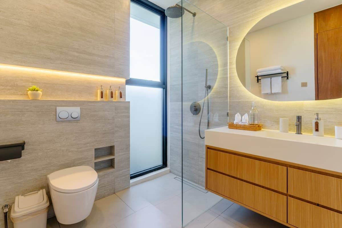 Bathroom with walk-in shower and backlit round mirror at Hubuddha Three Bedroom Villa Ubud Bali