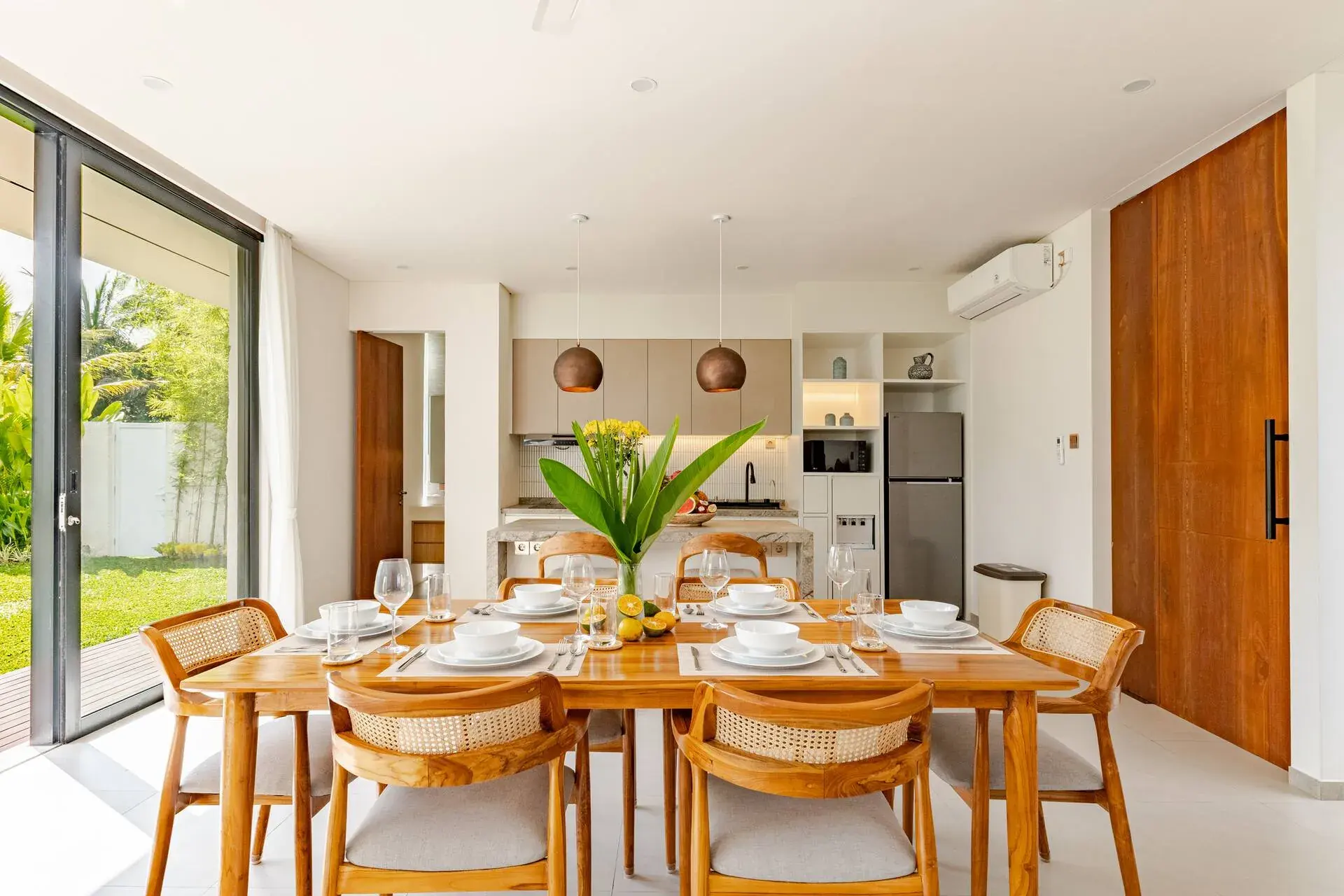 Cocina y mesa de comedor en la Villa 1, adyacentes a las puertas correderas hacia el jardín